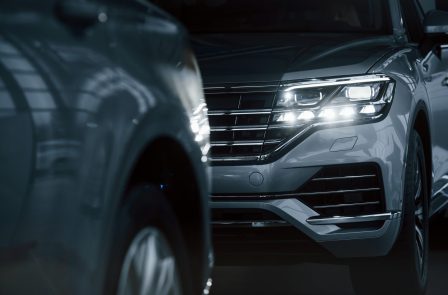 Powerful headlights. Particle view of modern luxury cars parked indoors at daytime Powerful headlights. Particle view of modern luxury cars parked indoors at daytime.